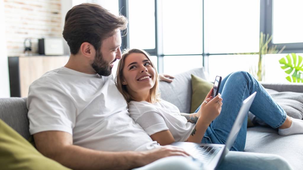 Happy young couple on a lounge using a laptop