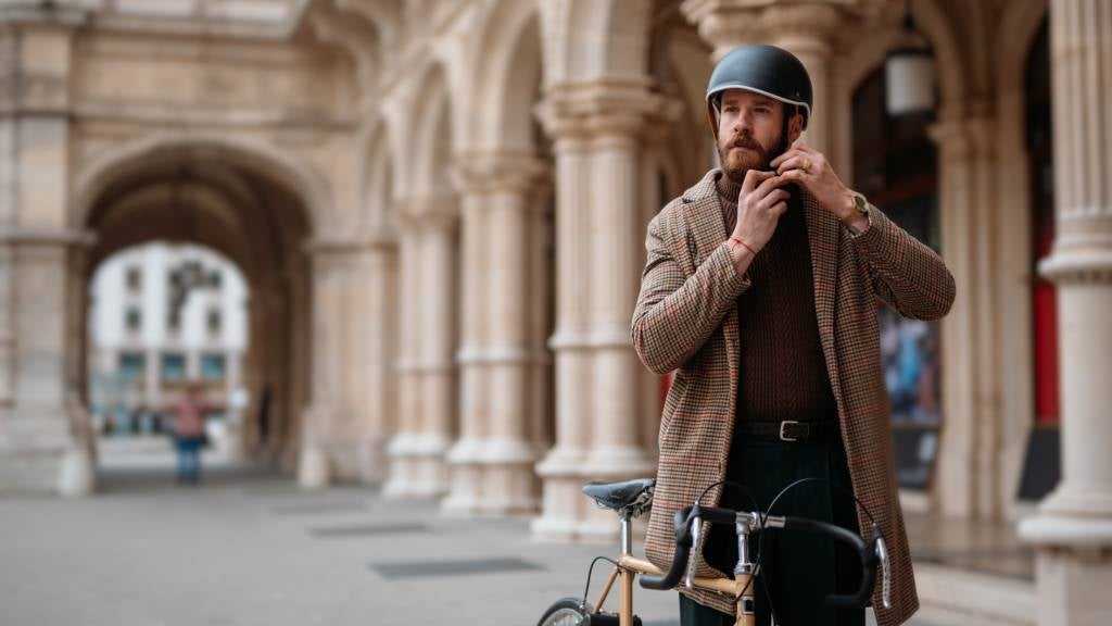 Hipster putting on a helmet before riding his bike