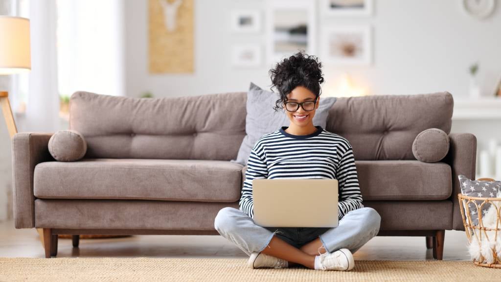 Woman searching her laptop while sitting in the living room