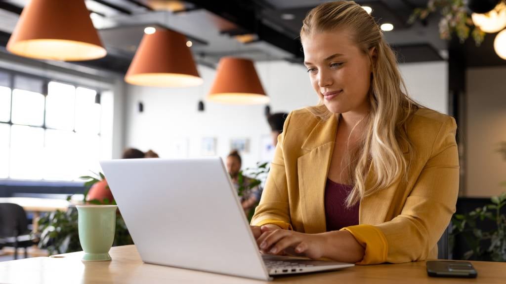 A professionally dressed woman types on her laptop