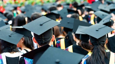 University students at an assembly standing together in graduation caps and gowns