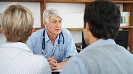 Doctor speaking with patients across the table