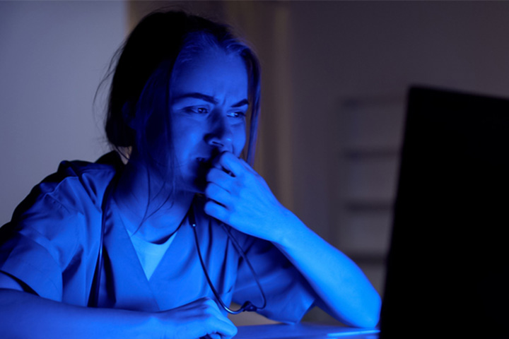 Distressed health practitioner looking at laptop screen