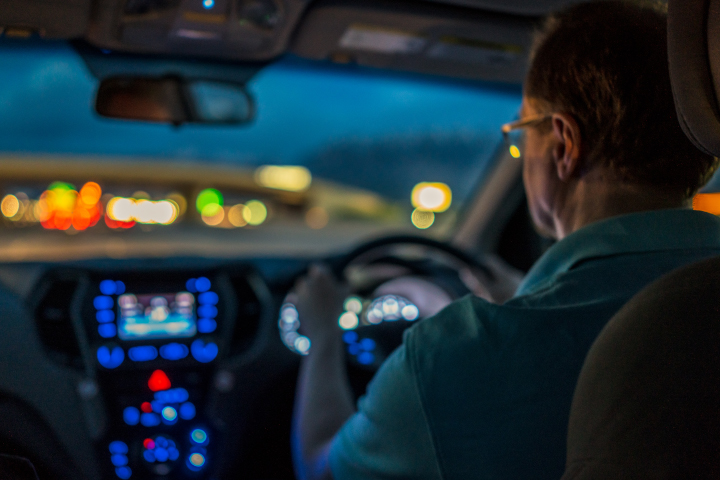 Behind shot of middle-aged man driving at night