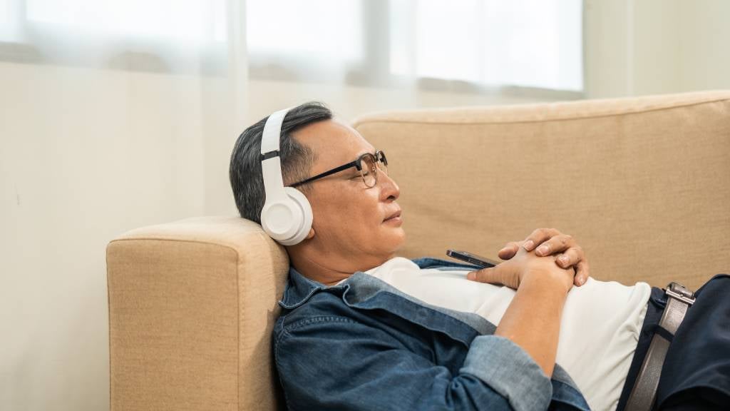 Man lays down on lounge with headphones on