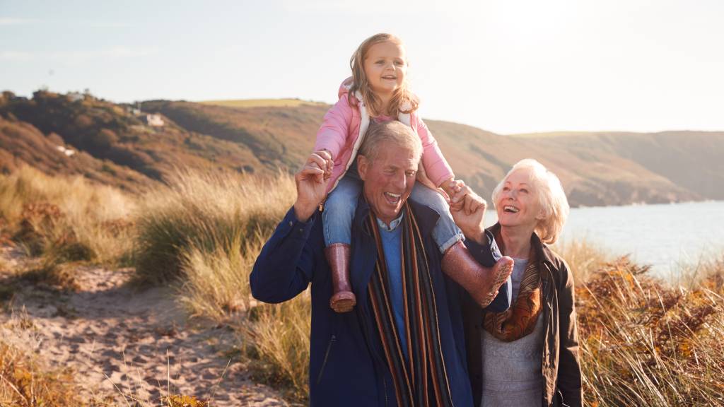 grandparents walking with granddaughter on beach