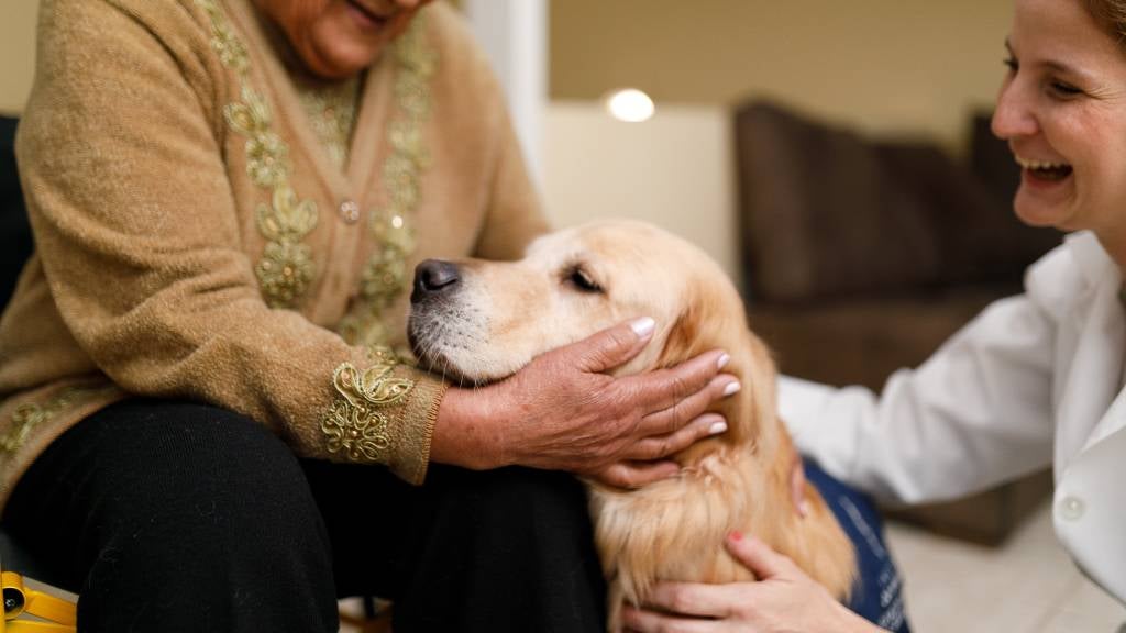 Senior woman and caregiver with therapy dog 