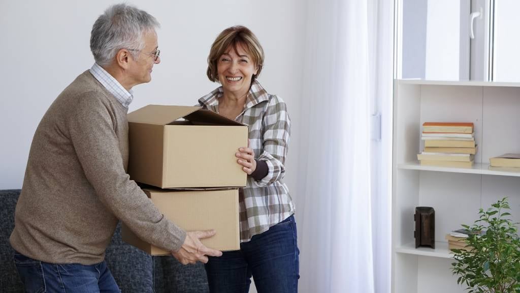 Senior couple carrying boxes while moving homes