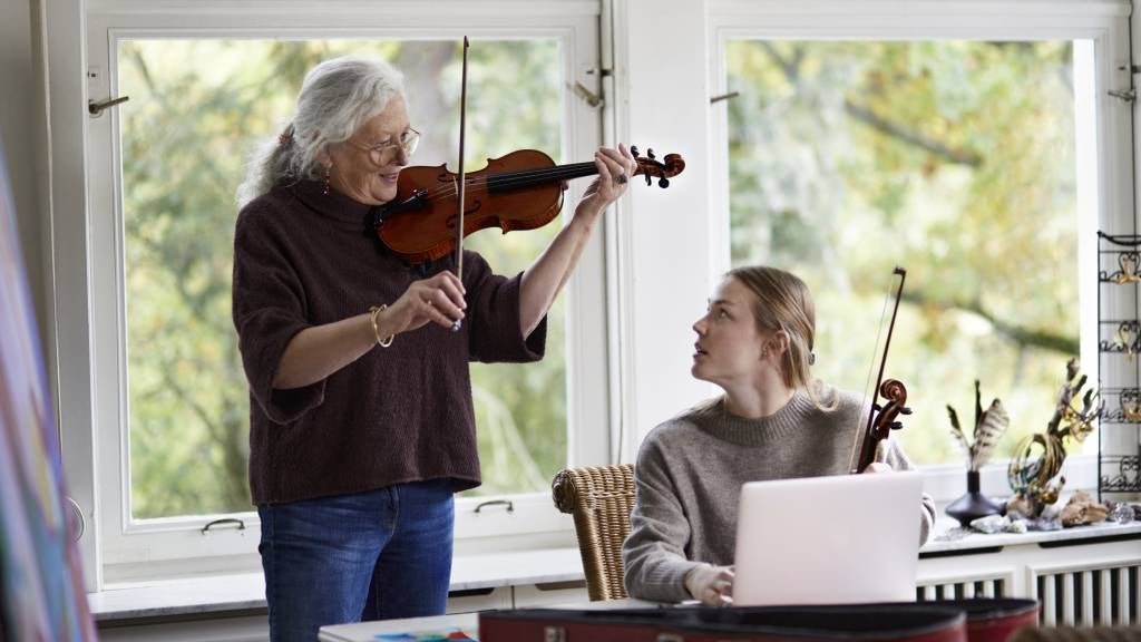 Senior woman tutoring a young girl to play violin
