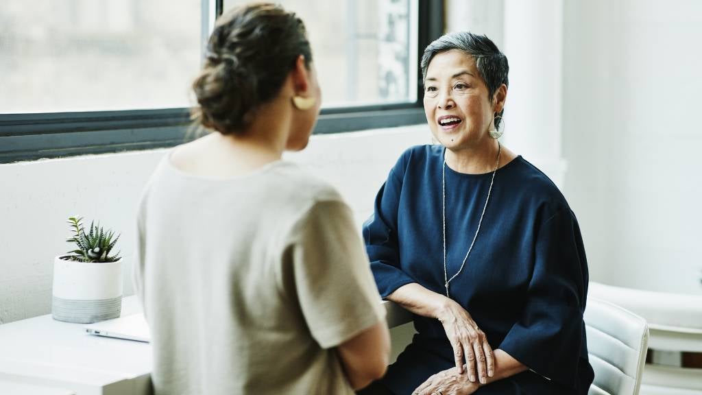 Two older women networking in a conference room 