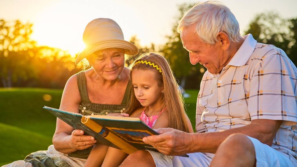 Senior couple read book with grandchild