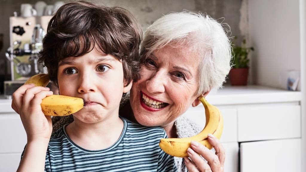 Grandmother and grandson playing at home with fruit