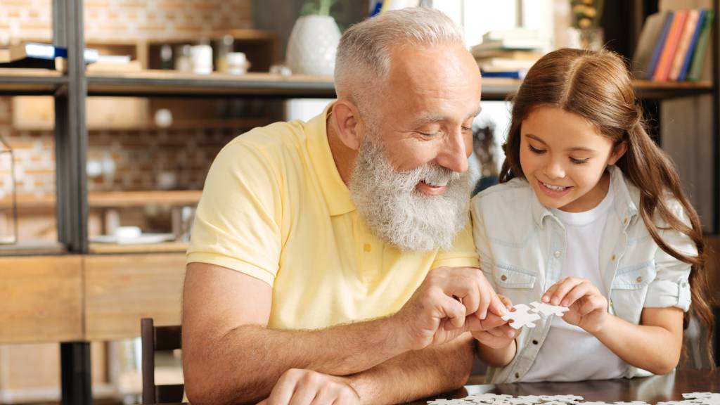 grandfather doing puzzle with young girl