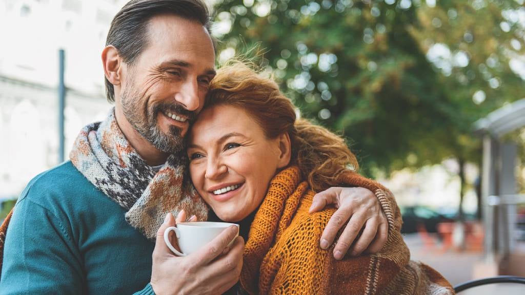 Happy couple embracing with a hug in a café holding a cup