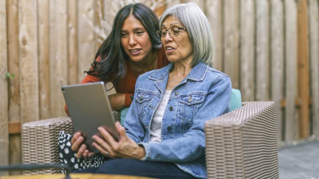 Mother and daughter talking through funeral information on a device.