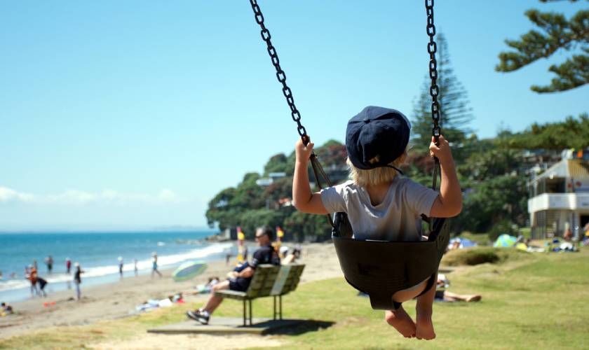 Child on a swing at a park in New Zealand's Auckland region