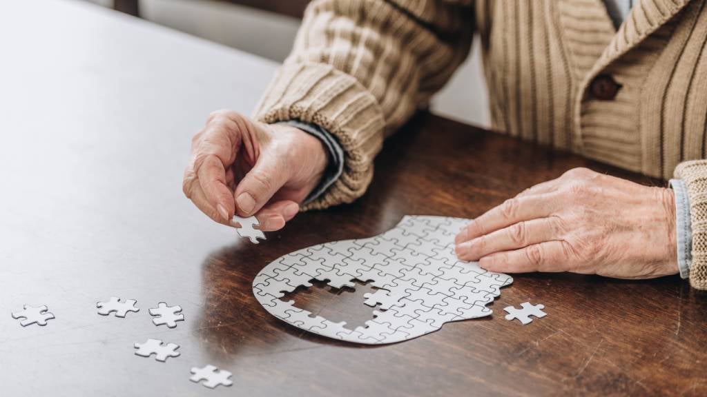 Man putting together a white coloured puzzle of a human head