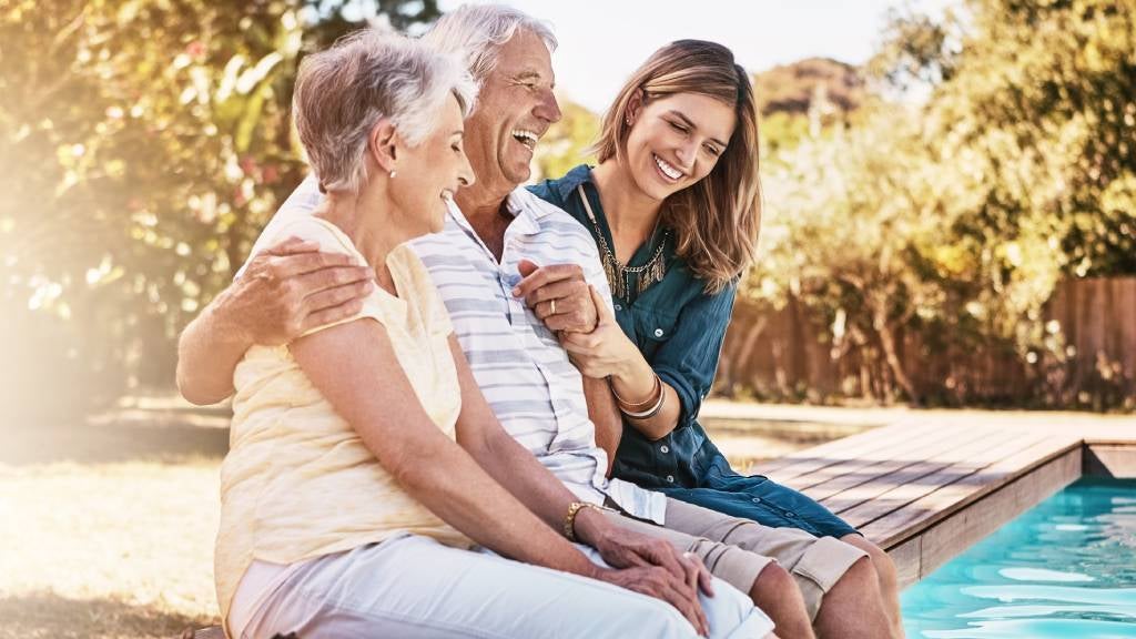 Mother and father sit poolside with daughter