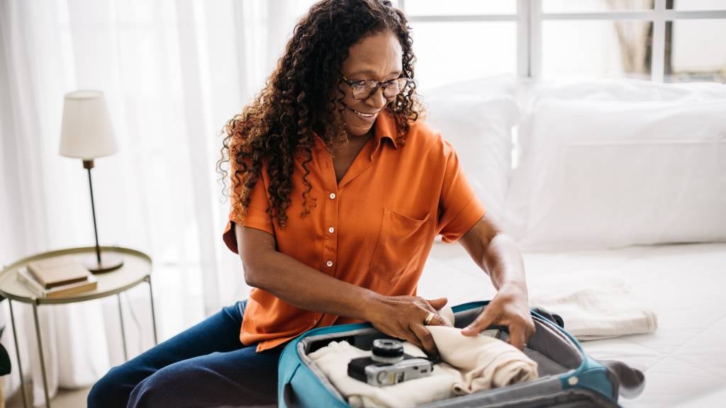 Woman packs suitcase for travel