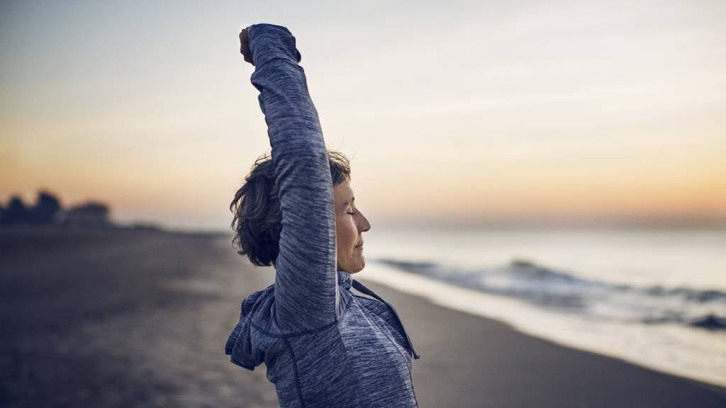 Senior lady stretching in front of the ocean