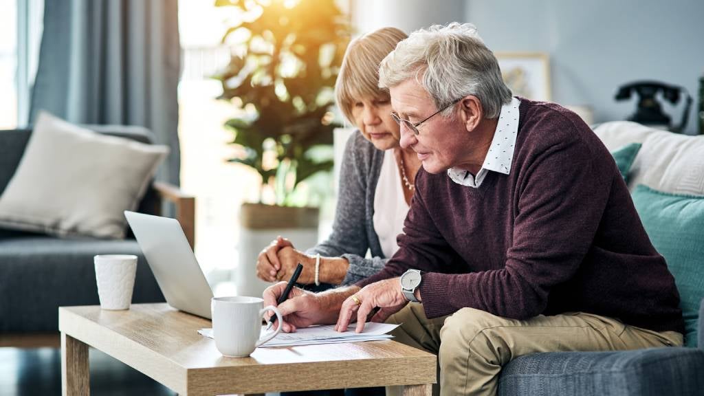 elderly couple on couch filling in documents