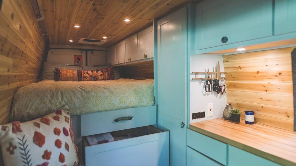 inside tiny home with tucked away bed and kitchen