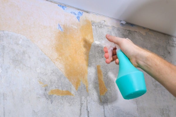 壁紙清除員在舊壁紙表面噴灑清除藥劑，以利後去的清除壁紙作業。