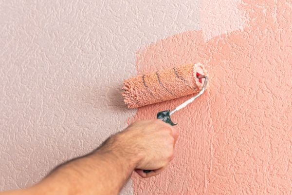 使用滾筒刷上粉色水泥漆