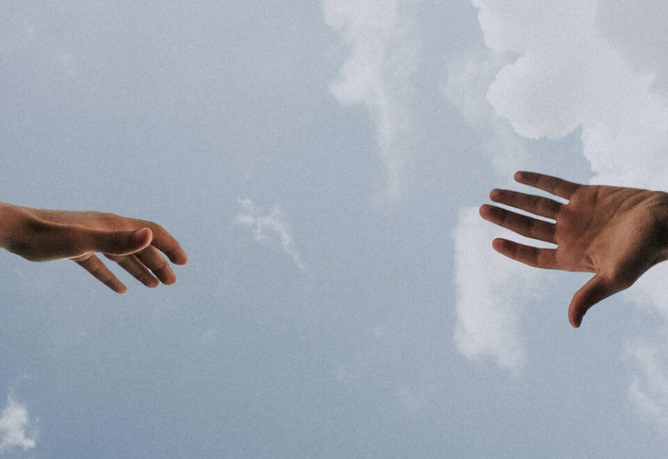 The Ethics Centre | two hands reaching out to each other with a cloudy sky in the background | Devotion