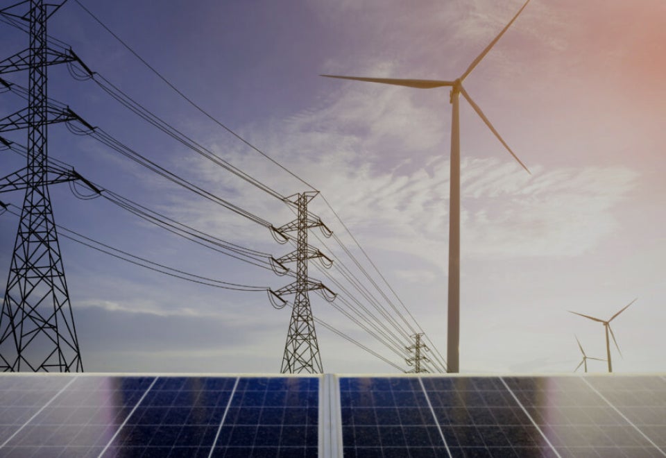 Yurika | A photograph of a solar panel in the foreground with high voltage power lines and wind turbines in the background | Devotion