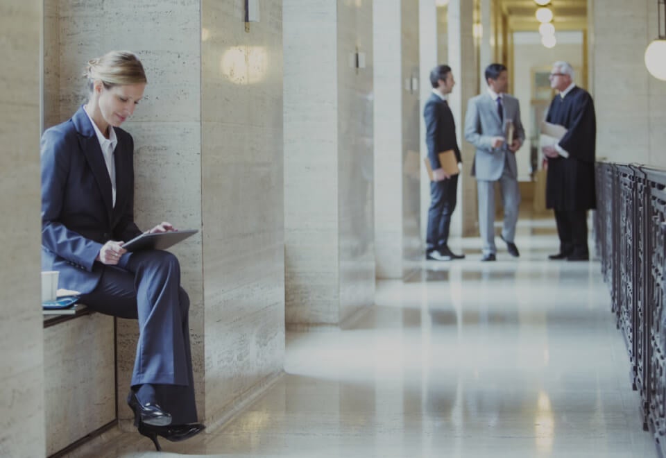 Lawyer sitting outside a courtroom using her tablet | MyCase | Devotion