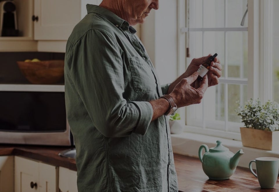 A man reading the label on a CBD oil bottle | Canwell Australia | Devotion